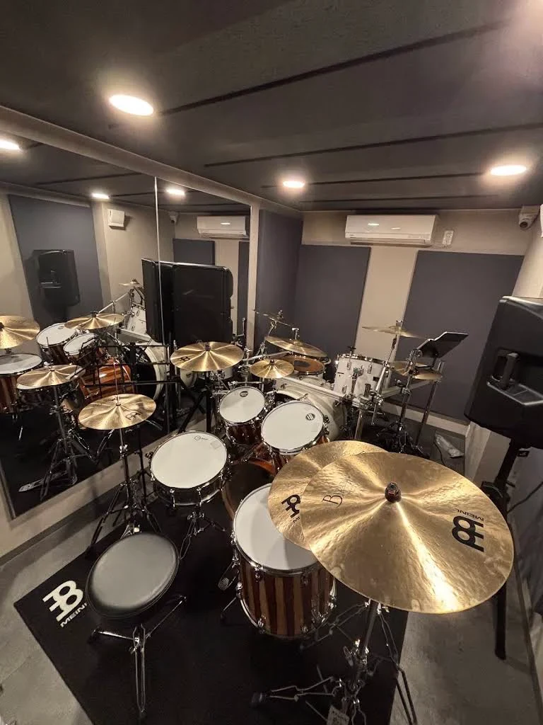STUDIO PORTのドラムルーム。鏡のある室内に設置されたドラムセットとシンバル